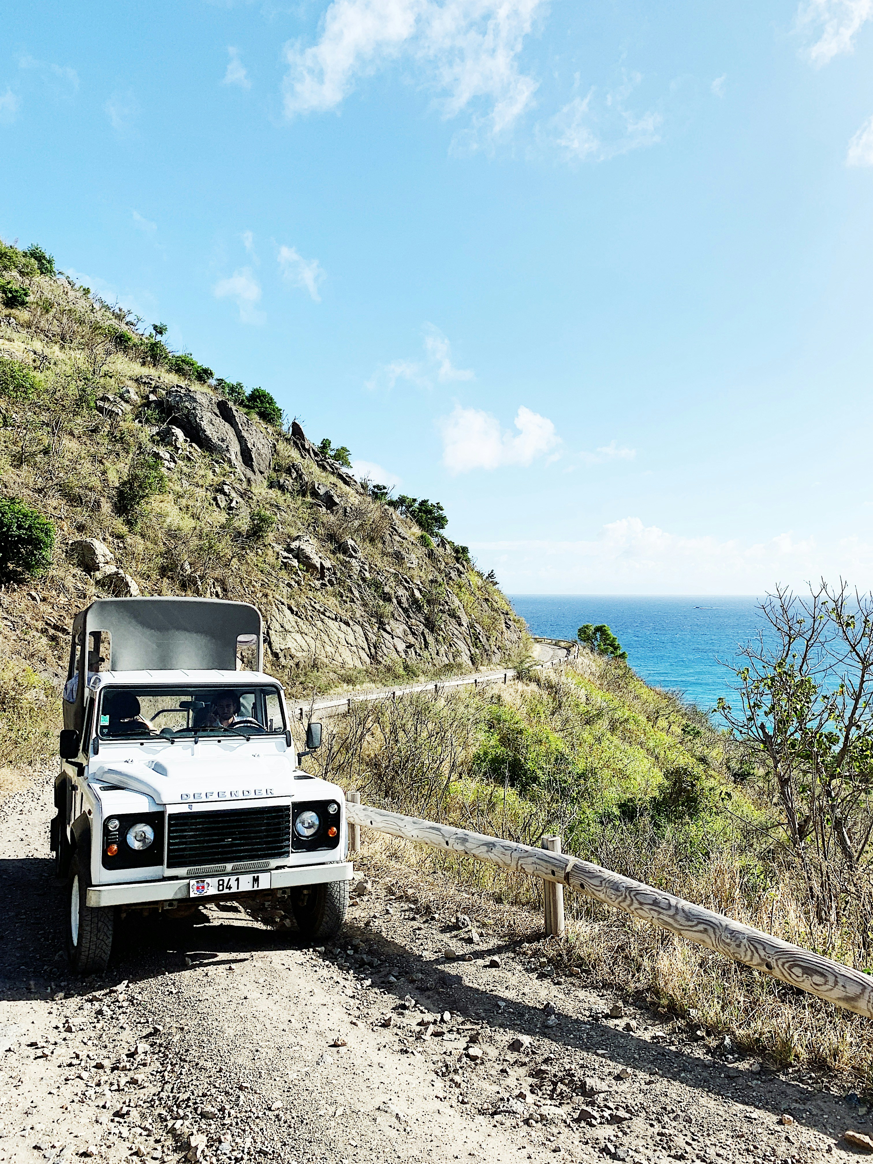selective focus photography of vehicle traveling on dirt road during daytime