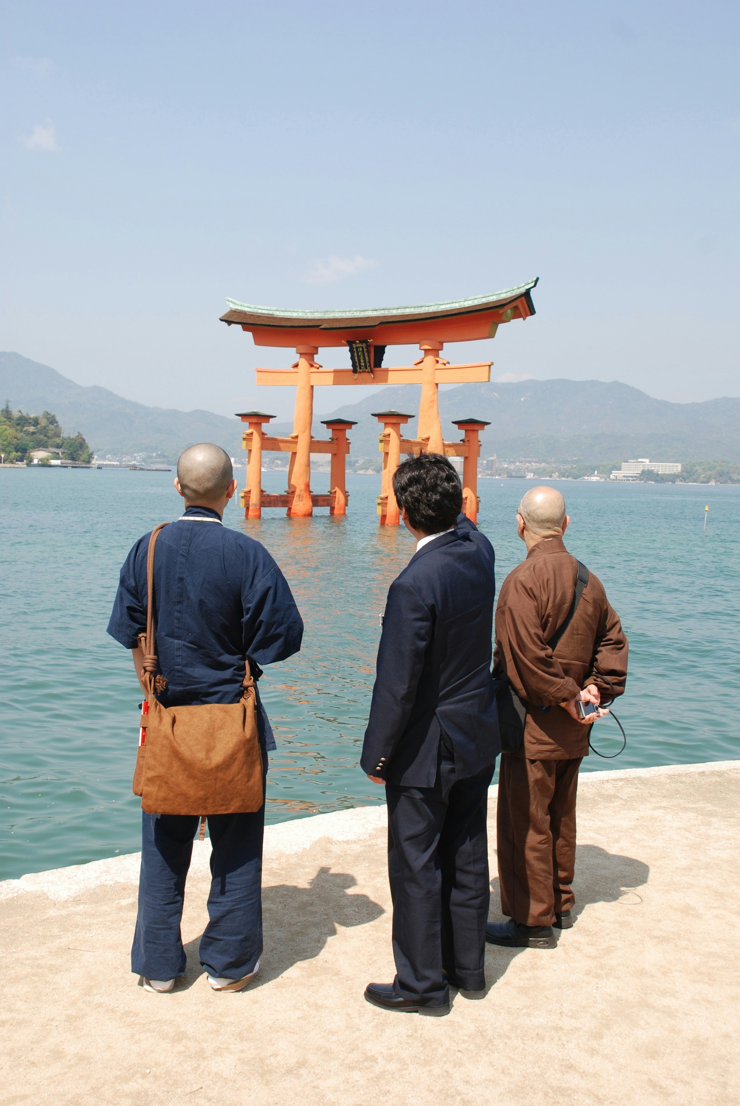 three men looking at body of water during daytime