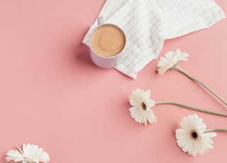 white ceramic mug near white flowers