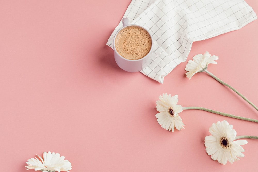 white ceramic mug near white flowers