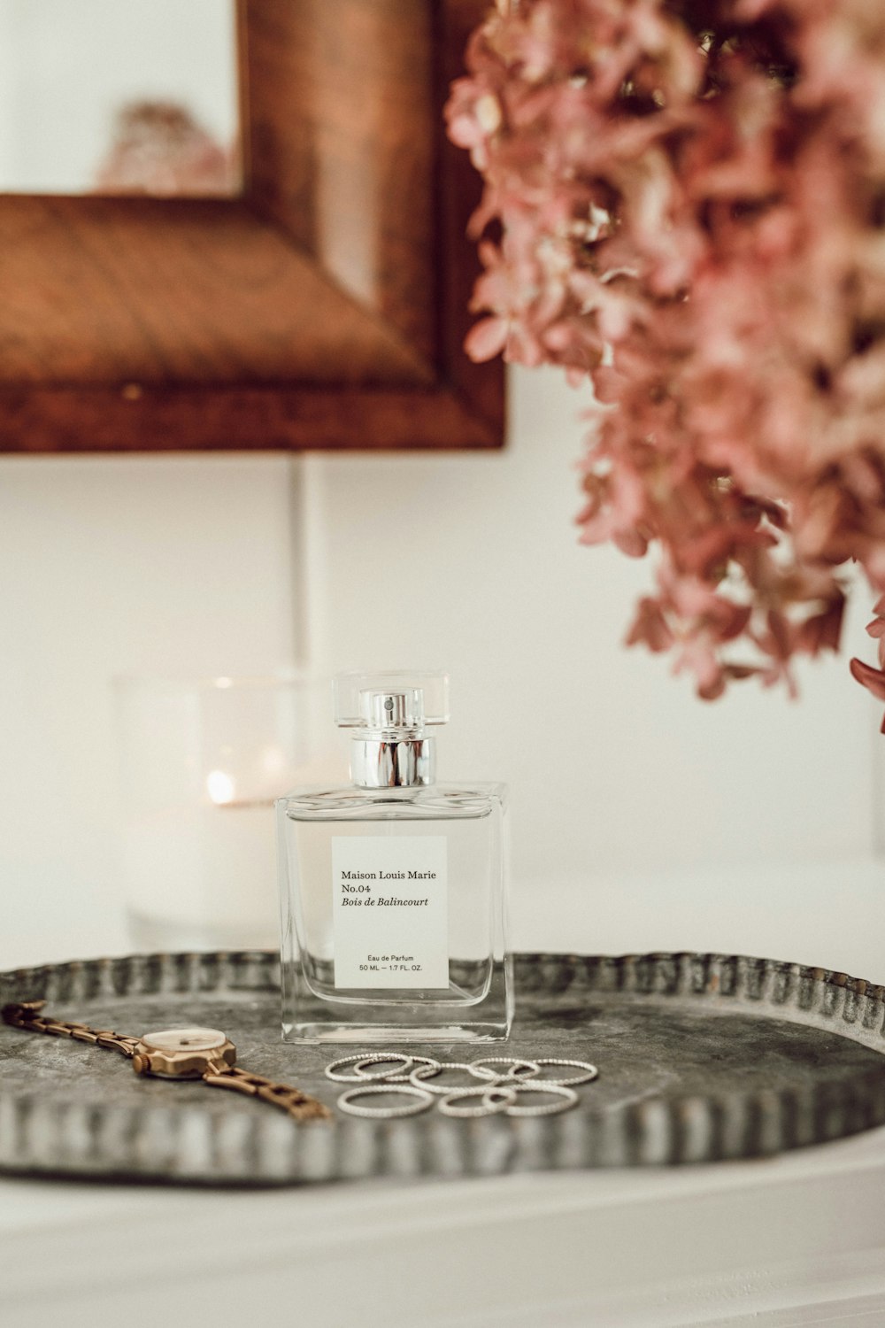 clear glass fragrance bottle beside gold-colored watch