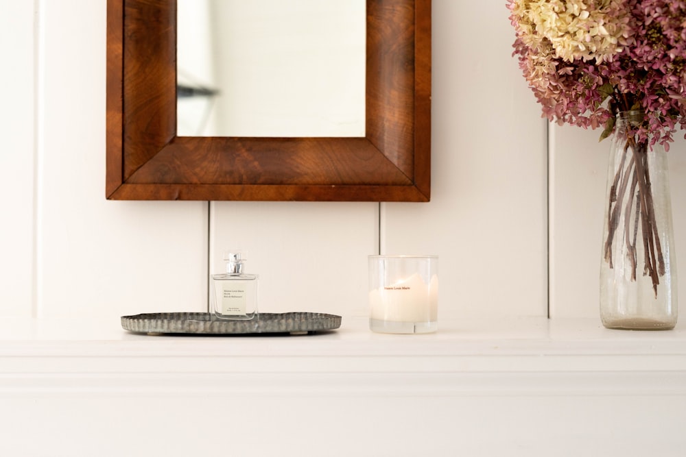 white candle beside clear glass flower vase