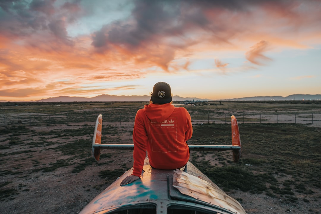 man sitting on top of an airplane at the field during day