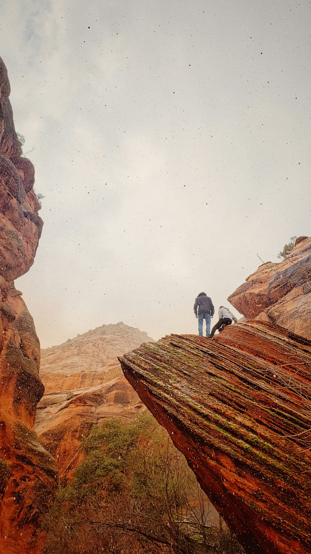 two person standing on mountain cliff