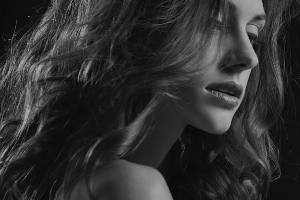 Close-up of a woman with a sleek, natural black wig styled elegantly in soft waves.