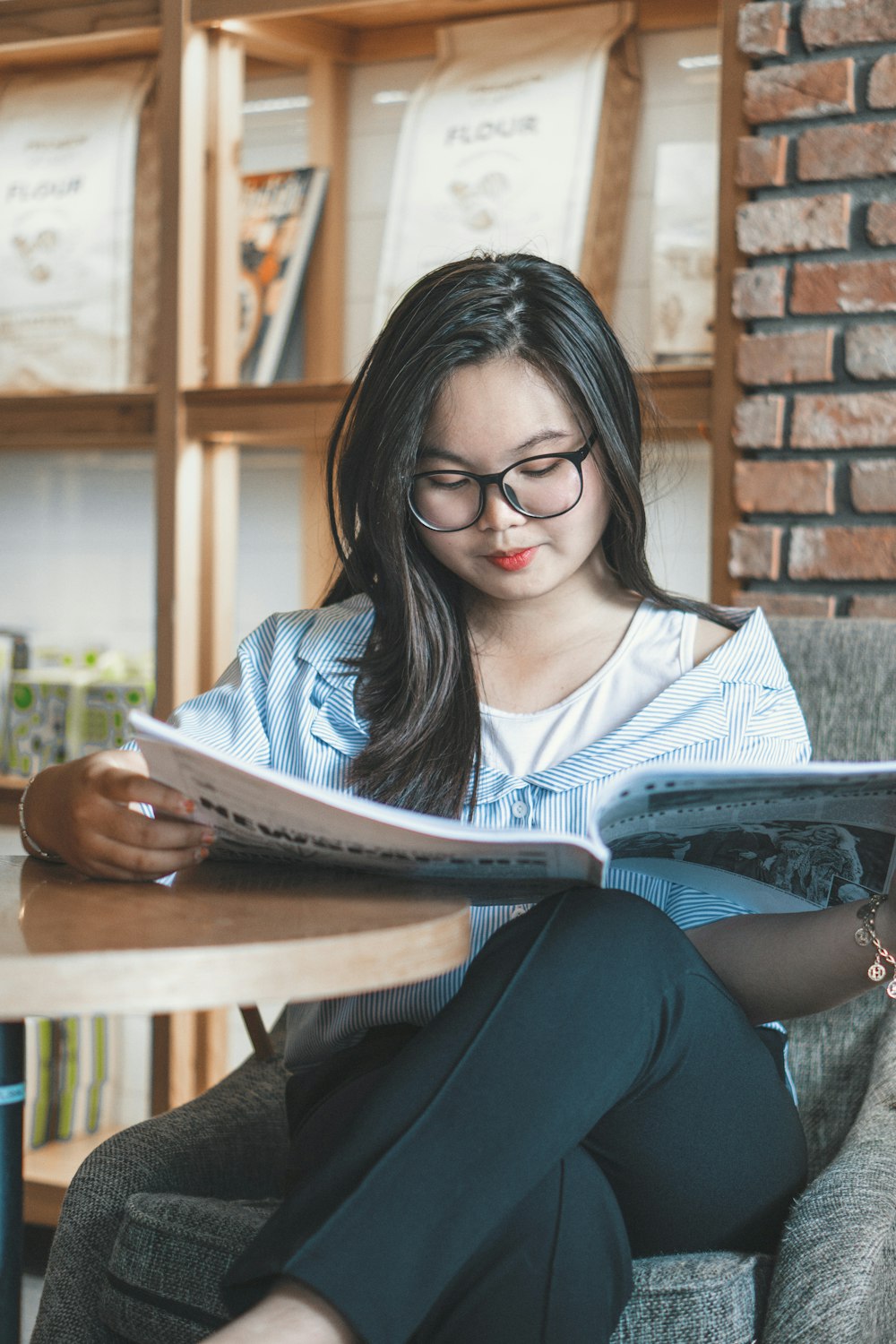 woman reading and sitting beside table inside room