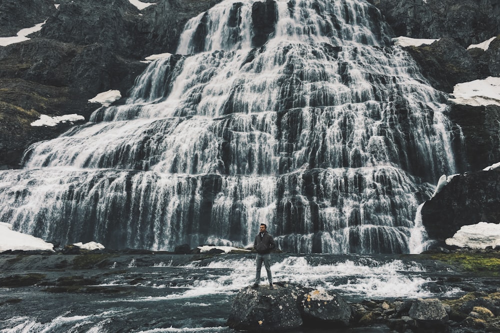 man standing near cascading waterfalls