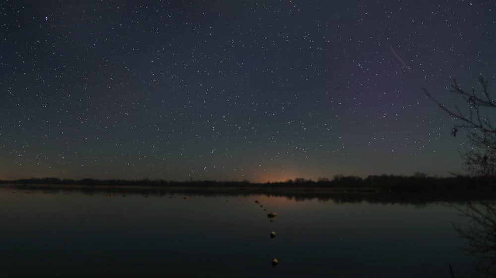 the night sky is reflected in the still water of a lake