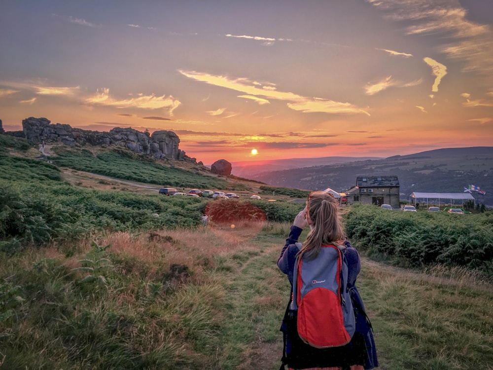 woman standing while taking picture at green field