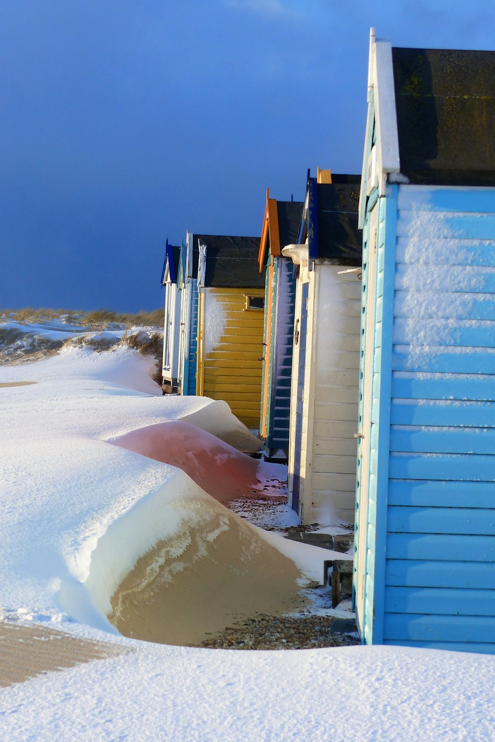 snow covered field with wooden sheds during day