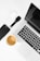 A well-arranged flat lay of modern tech gadgets placed on a white surface, including a sleek black smartphone, wireless earbuds in a white case, a black smartwatch, a silver laptop with a black keyboard, and a cup of coffee with a rich crema.