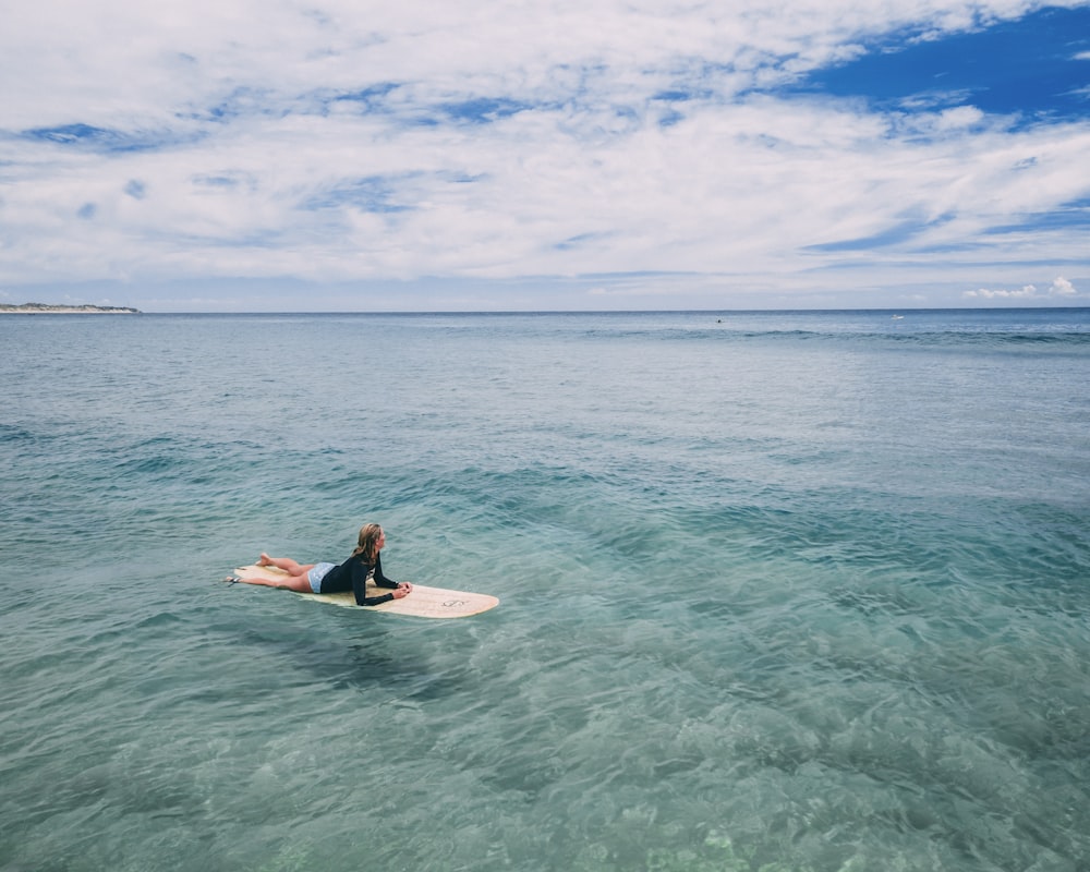 mulher deitada na prancha de surf