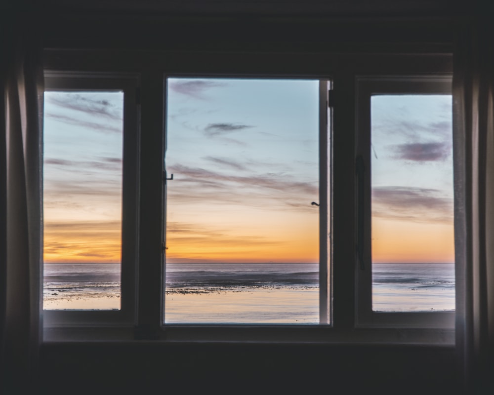 Ventana de vidrio con marco de madera blanca cerca del cuerpo de agua