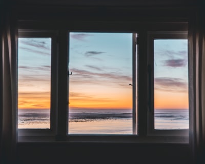 white wooden framed glass window near body of water window google meet background