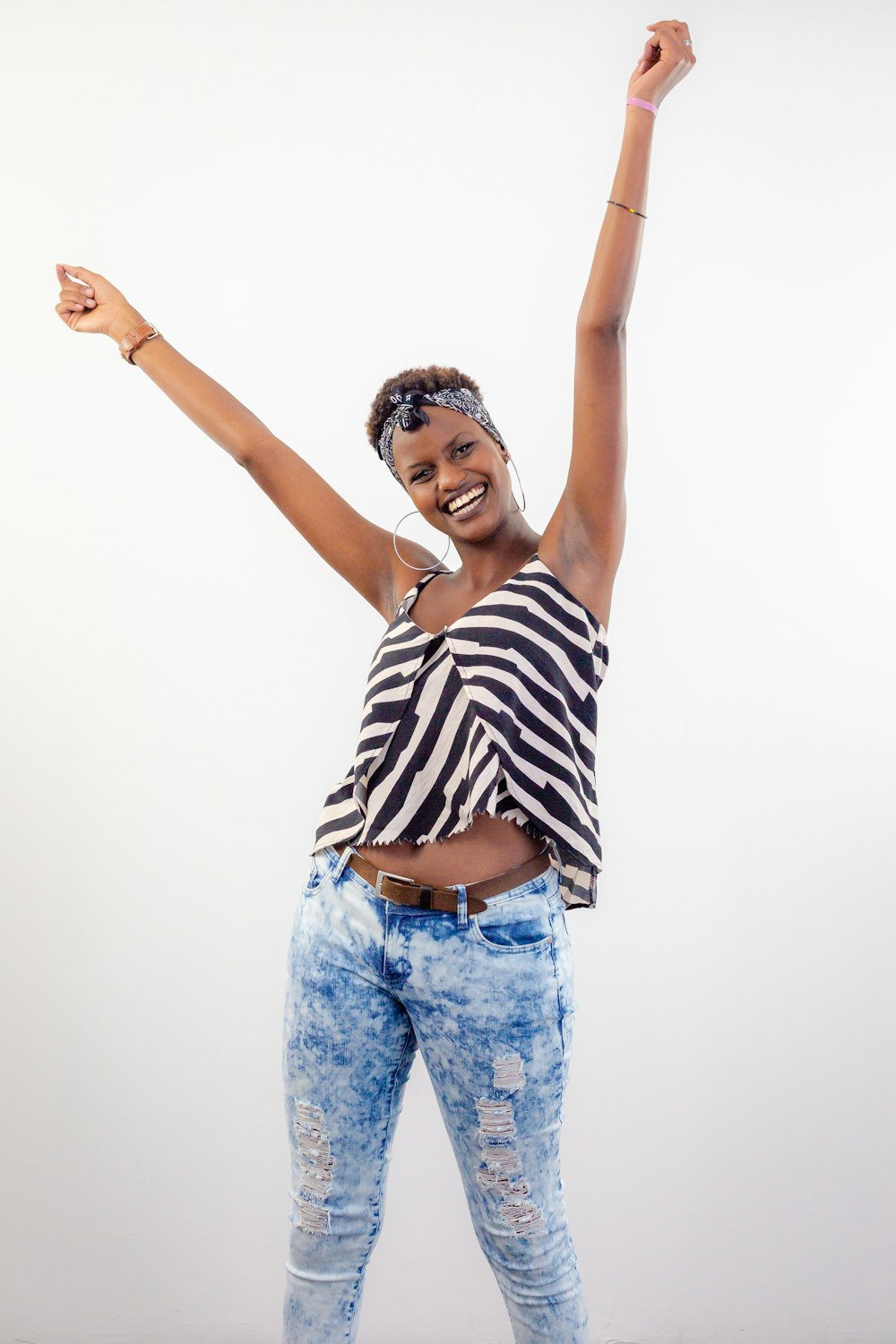 woman in white and black striped crop-top raising her hands