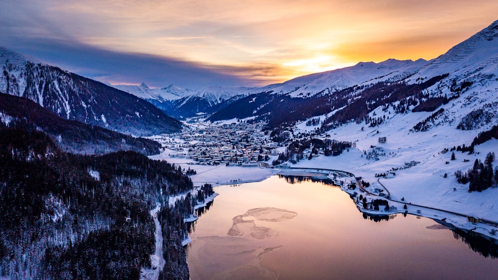 body of water near mountain covered by snow