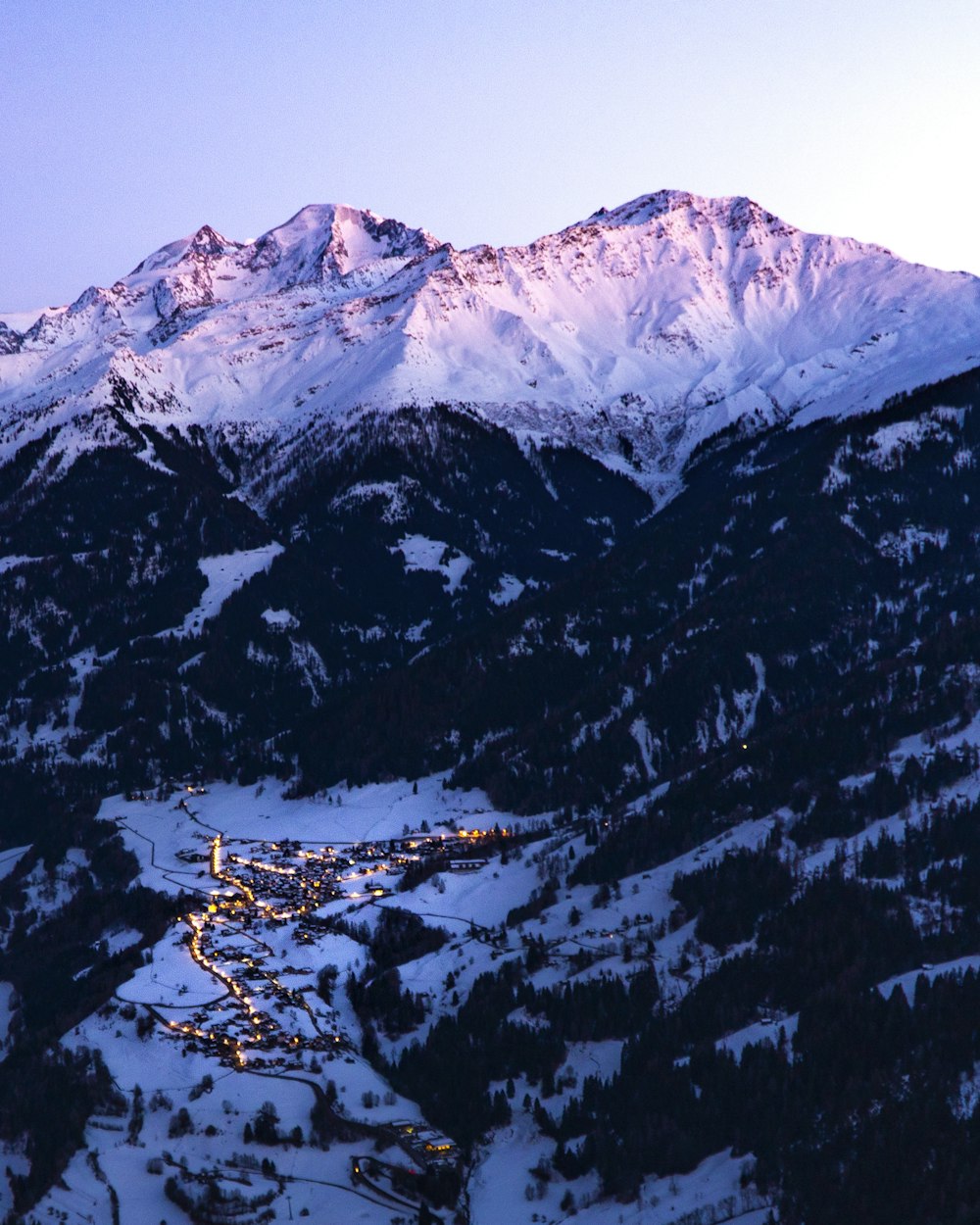 houses surrounded by snow covered mountain during daytime