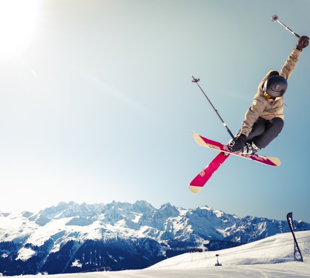 person in brown jacket doing snow ski blade trick