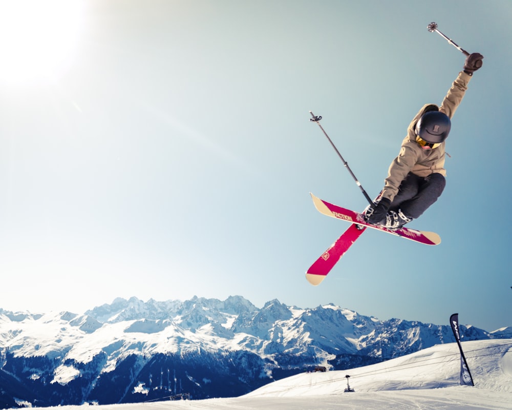 person in brown jacket doing snow ski blade trick