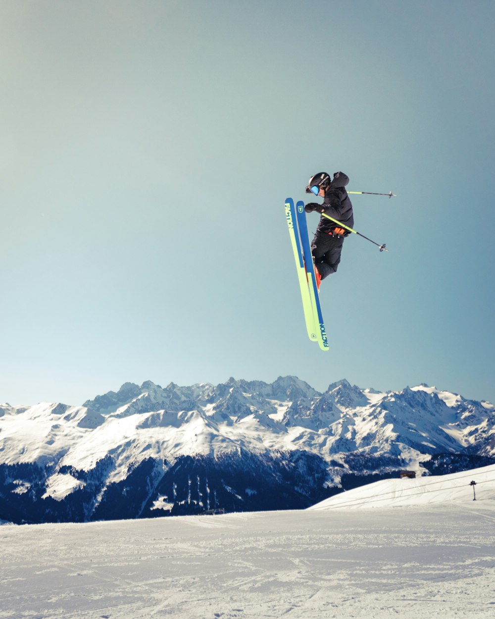 person jumping with skis and ski poles above snowfield