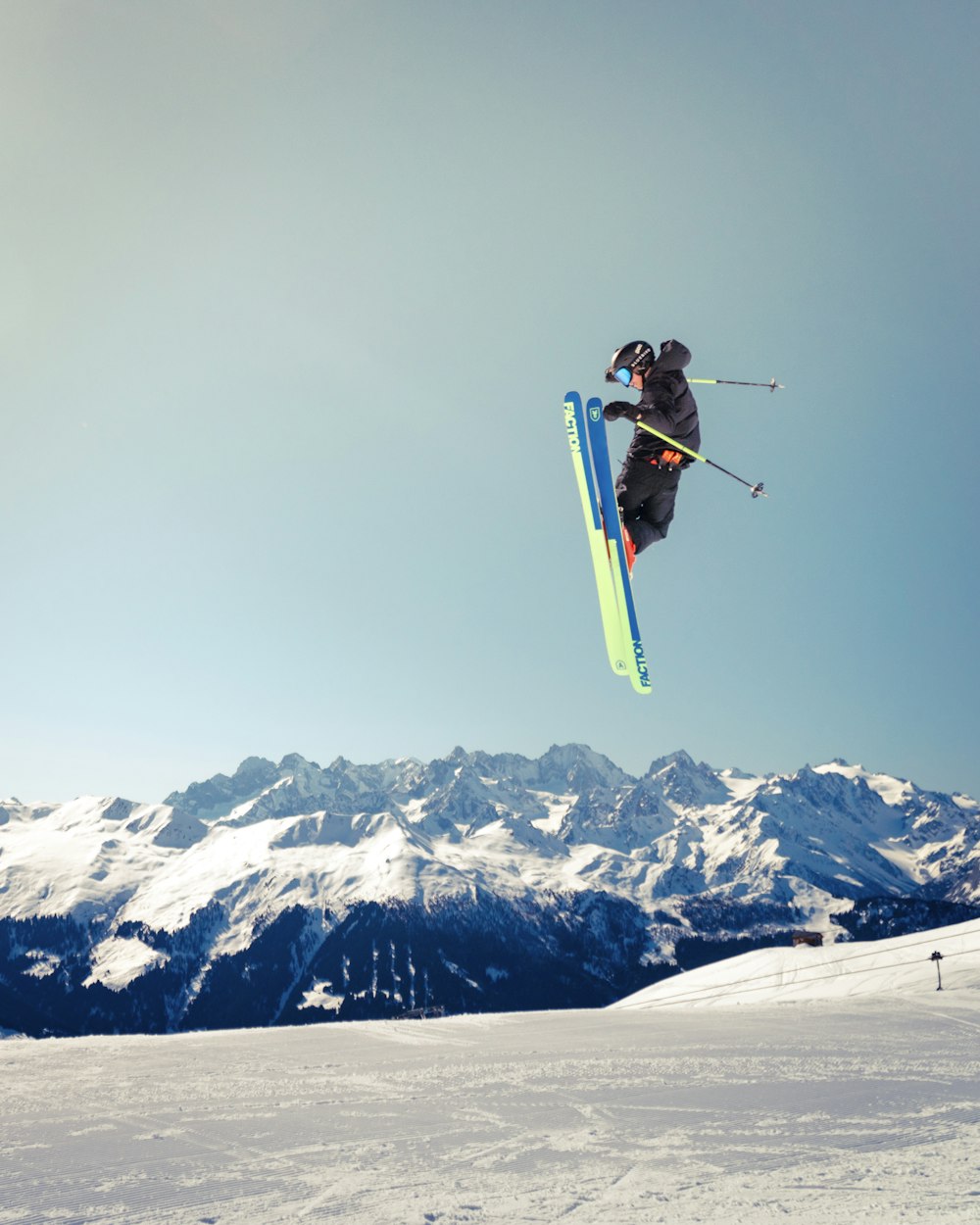 Person, die mit Skiern und Skistöcken über Schneefeld springt