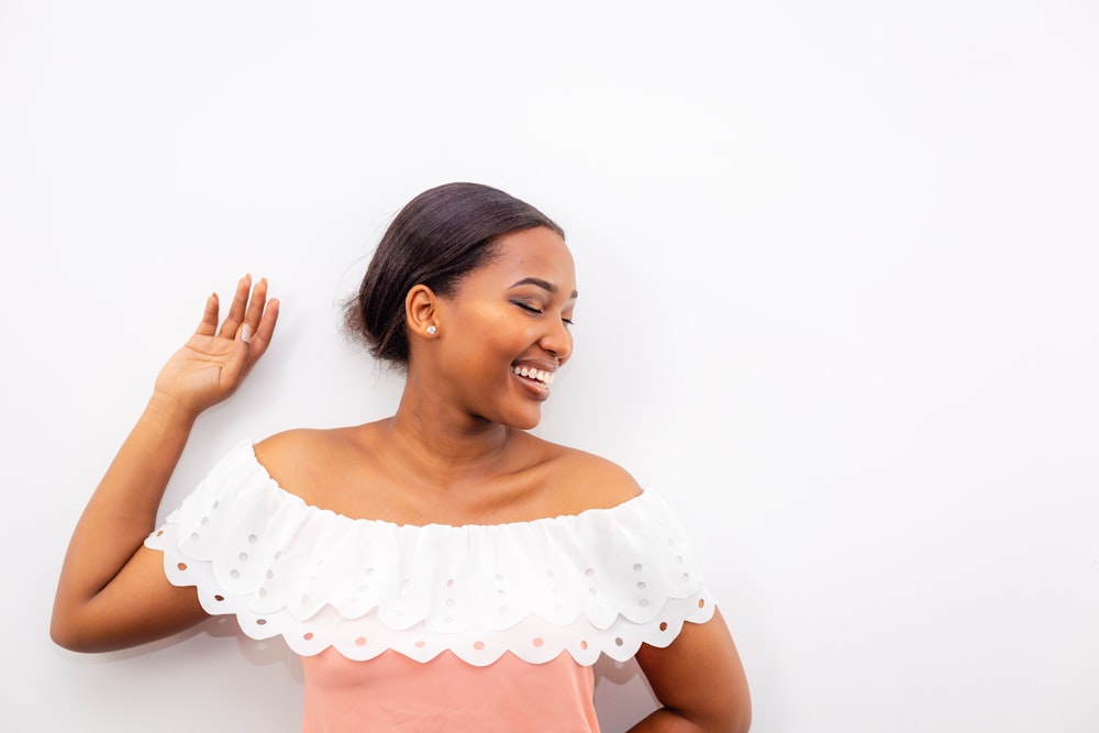 woman in white bertha collar blouse leaning on white wall