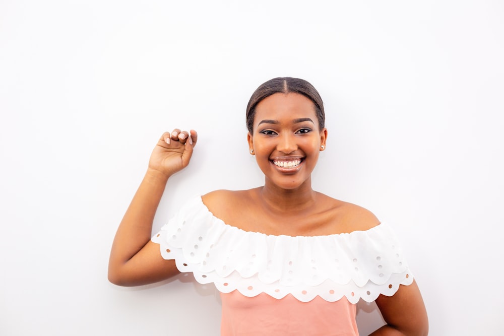 woman in white and pink off-shoulder top standing beside wall