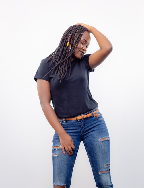 Model wearing a relaxed-fit t-shirt in muted blue, standing against a simple white wall.