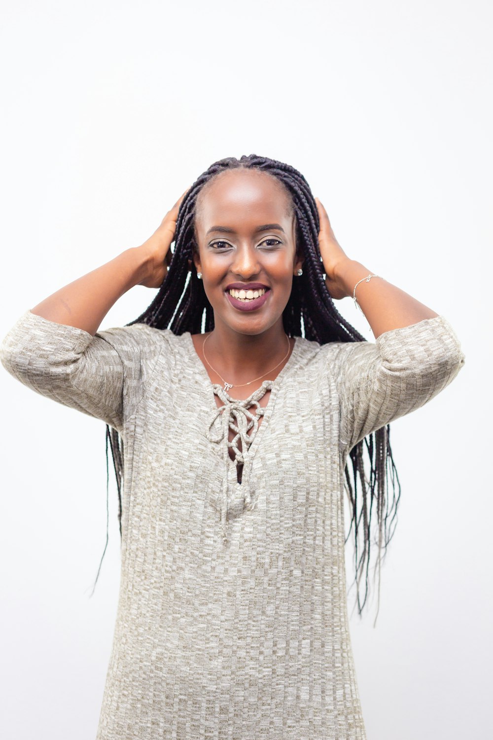 woman wearing gray 3/4-sleeved dress holding her braided her