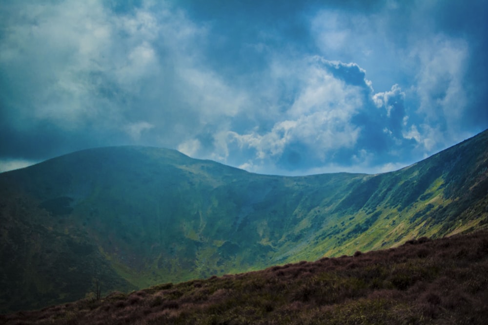 green mountain under white and blue cloudy sky