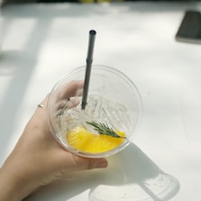 Close-up of a hand pouring a vibrant aqua fresca into a clear cup with ice.