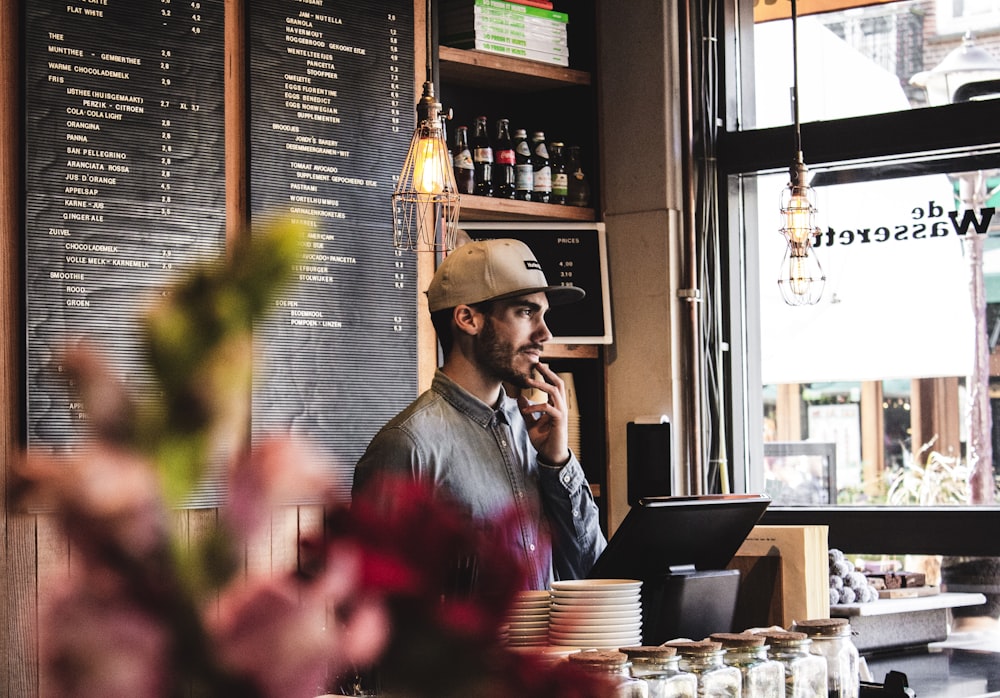 man wearing brown cap in across menu board