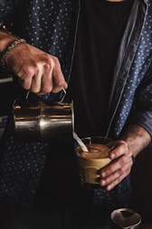 person pouring milk on coffee
