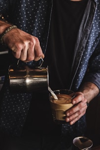 person pouring milk on coffee