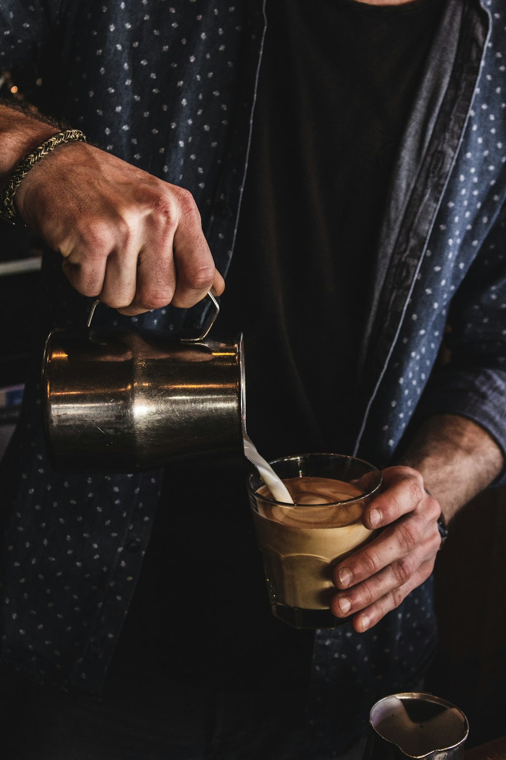 person pouring milk on coffee