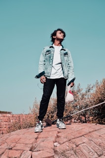 A young man wearing a sharp military-style jacket paired with casual sneakers, standing confidently outdoors.