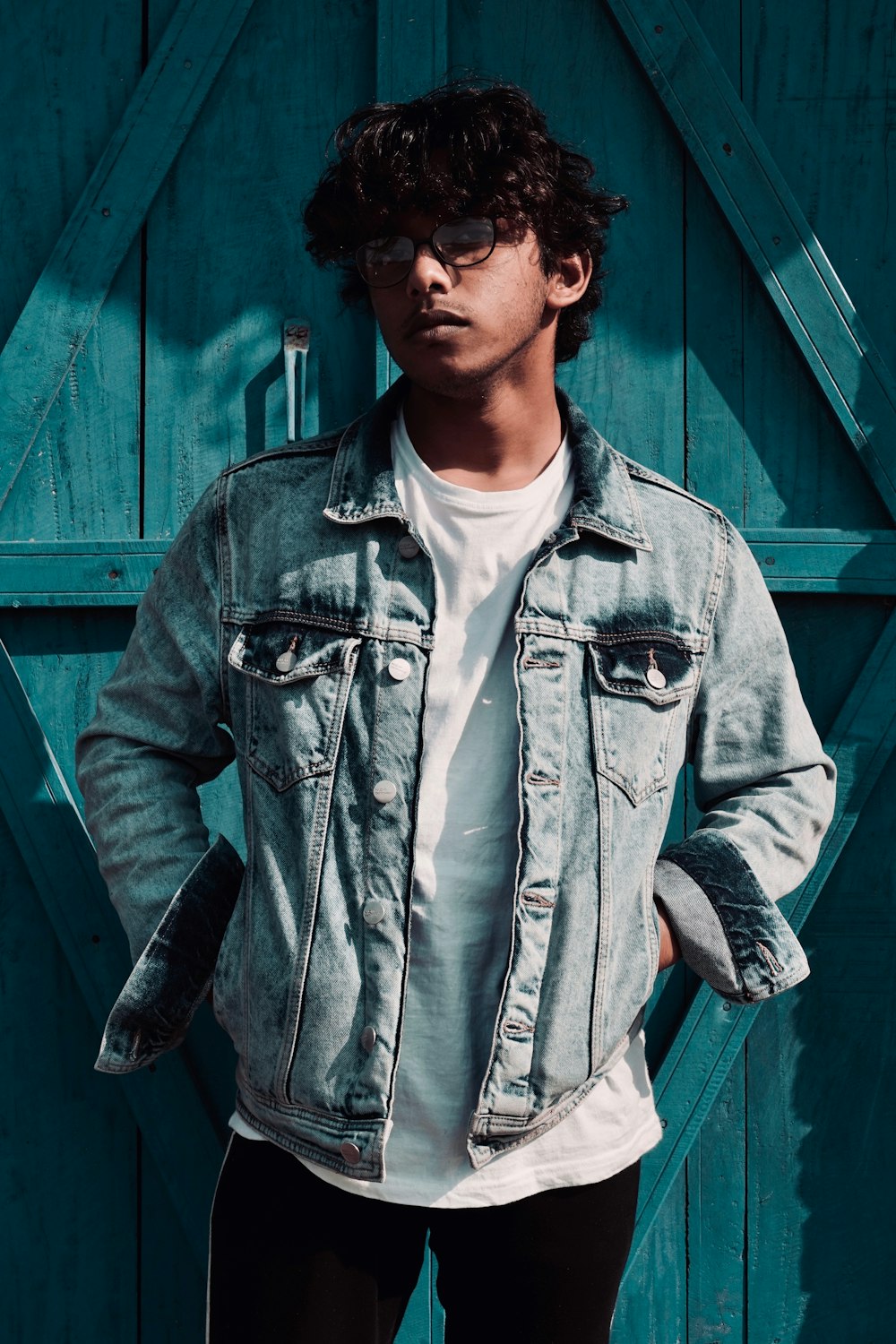 man standing beside blue wooden wall