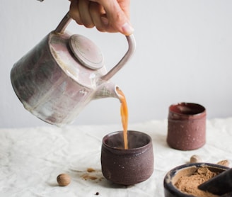 person pouring coffee on brown cup