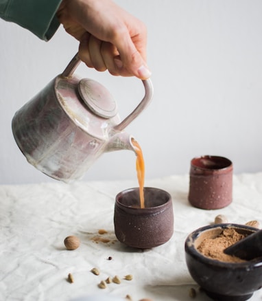 person pouring coffee on brown cup