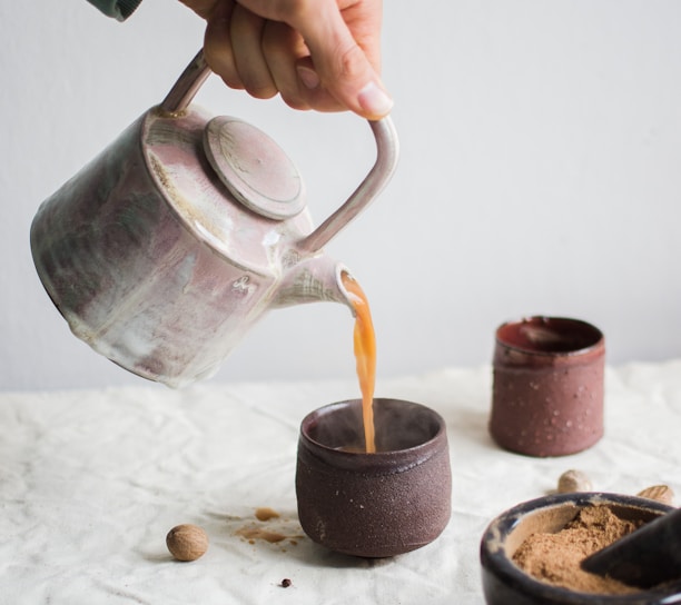 person pouring coffee on brown cup