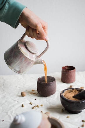 person pouring coffee on brown cup