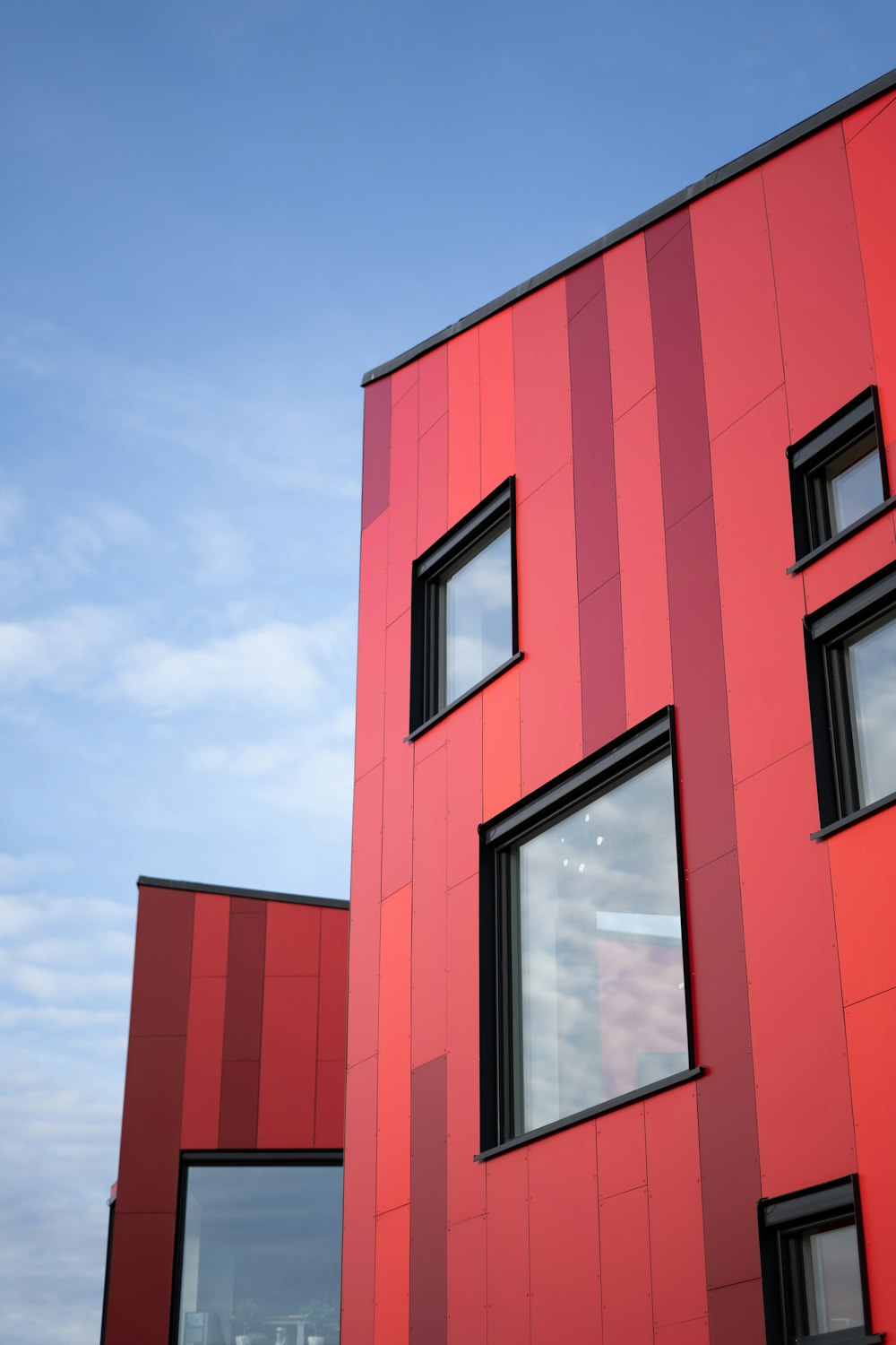 a red building with three windows and a sky background
