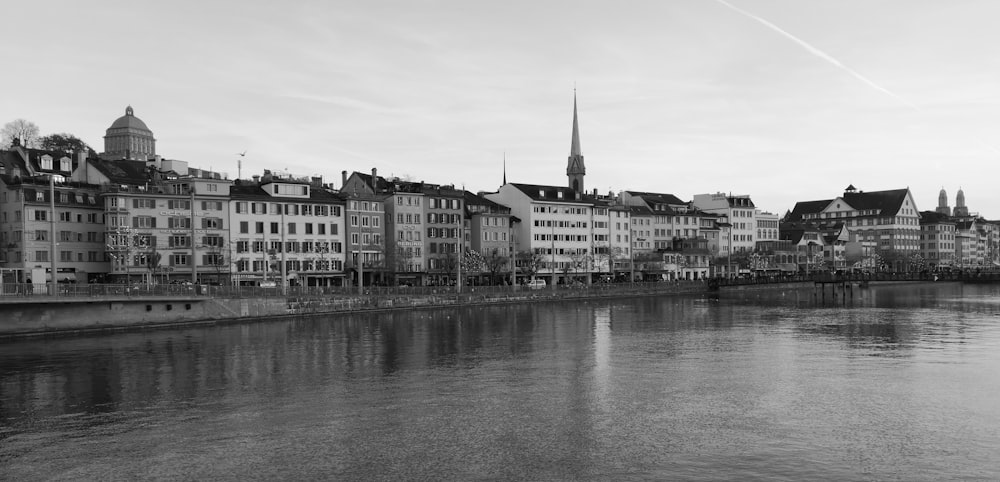 grayscale photo of buildings beside body of water