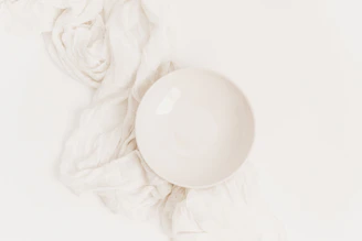 Close-up of a smooth, minimalist white ceramic bowl on a kitchen counter.