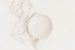 Close-up of a smooth, matte white ceramic bowl with sharp edges on a pure white background.