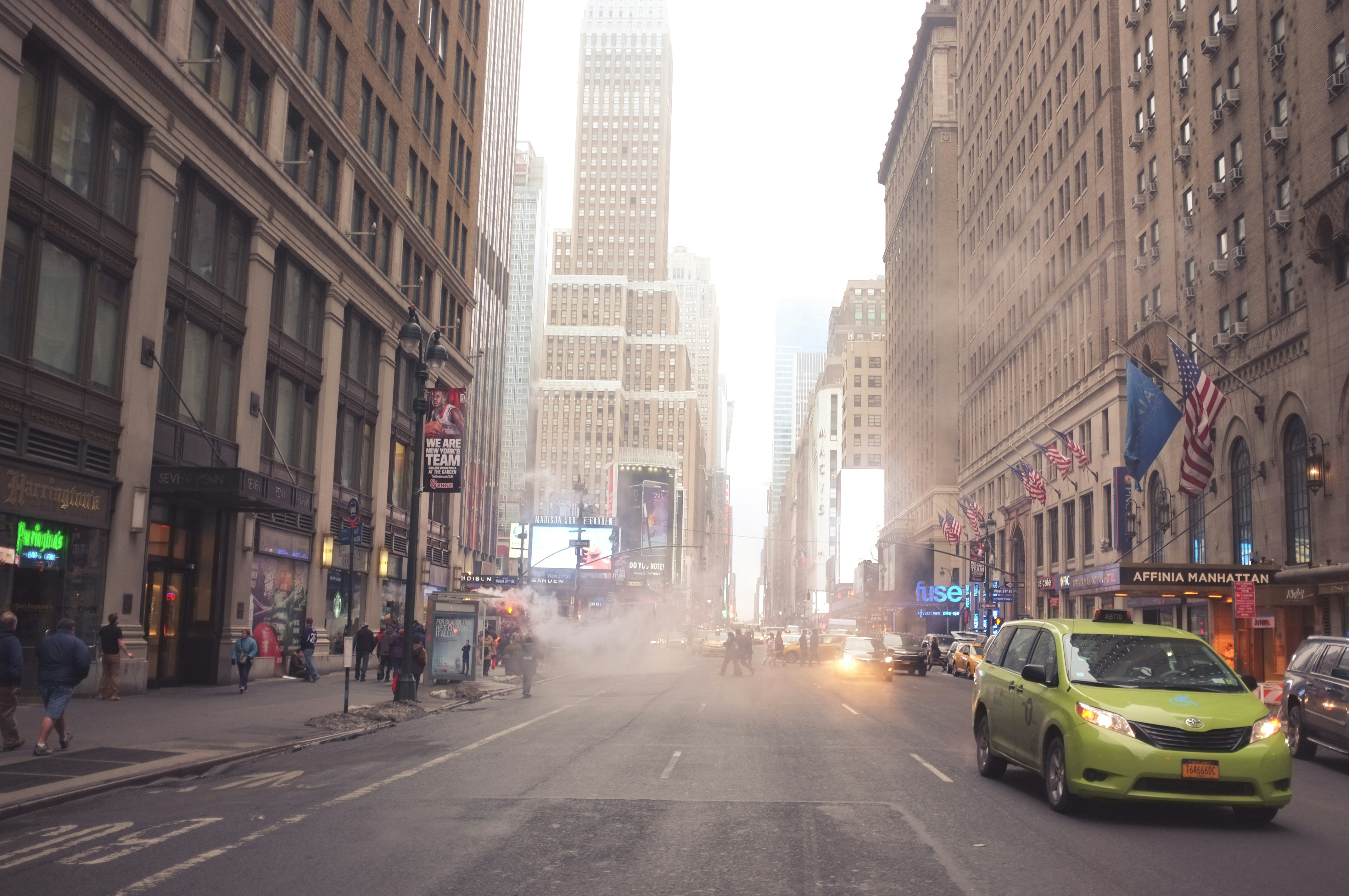 A shimmering road in a city during extreme heat, with visible heat haze distorting buildings, and a digital thermometer displaying 48-49 degrees Celsius prominently.