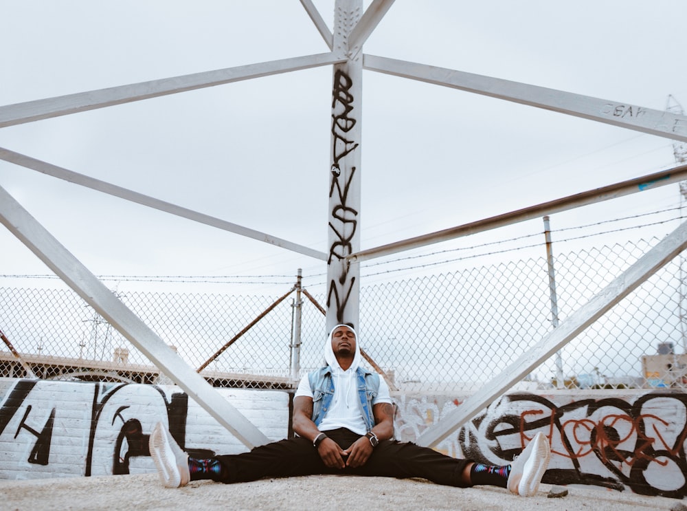 man sitting beside white metal stand