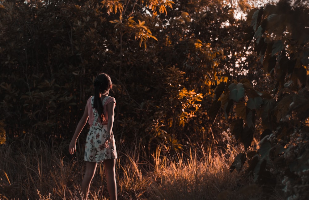 girl walking on brown grass near trees during daytime