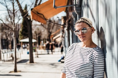 woman leaning on wall wearing sunglasses and striped shirt splendid google meet background