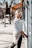 a woman leaning against a building on a sidewalk